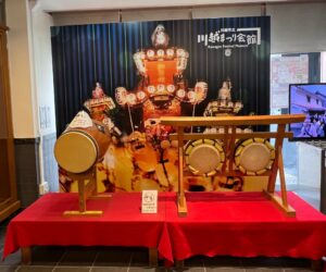 川越まつり会館に展示されたお囃子の太鼓と山車の写真パネル